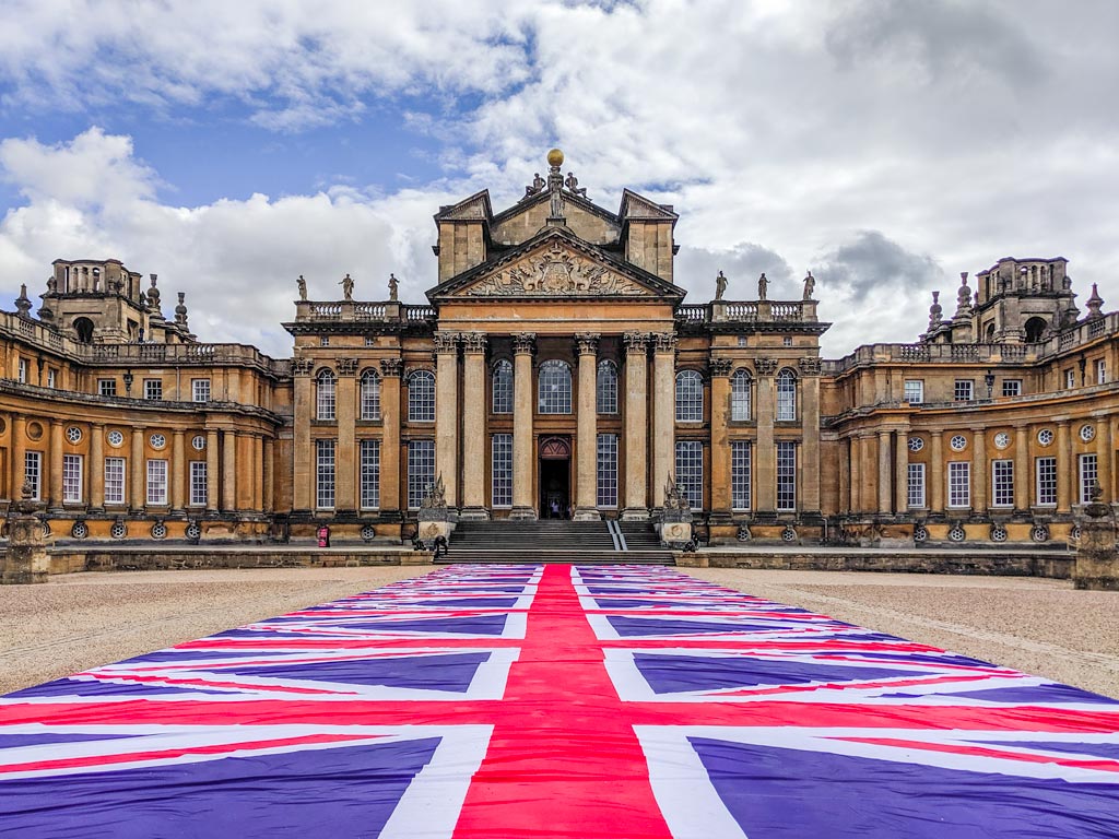 Exterior of Blenheim Palace with union jack flag runner, among the top uk bucket list ideas in England.