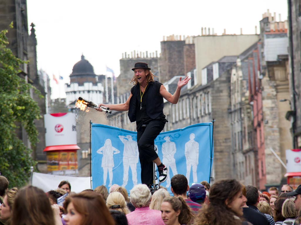 Man juggling fire in front of crowd at Edinburgh Fringe festival.