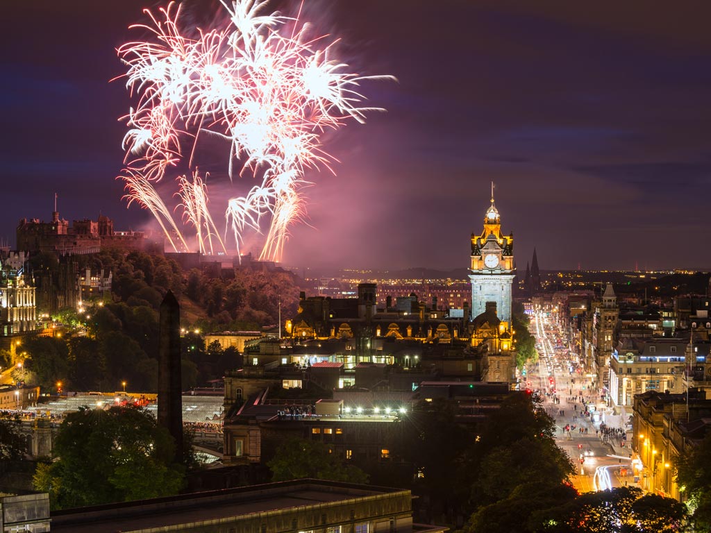 Aerial view of fireworks going off above Edinburgh city center.