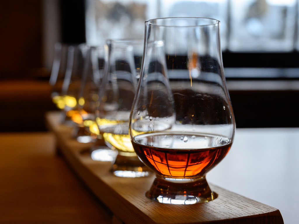 Row of Scotch snifter glasses partially filled.