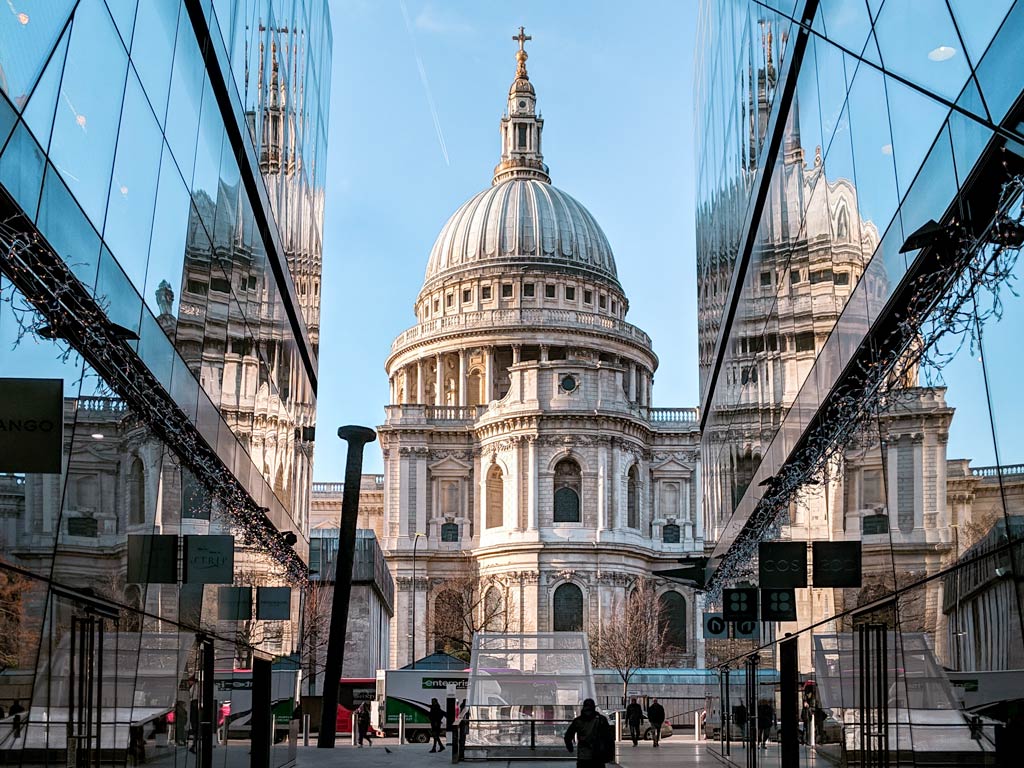 View of St. Paul's Cathedral from alleyway lined with glass buildings.