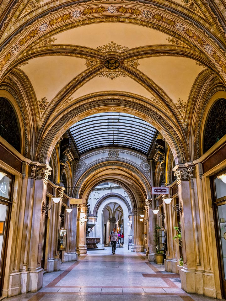 Vienna Ferstel Passage with golden arched ceiling and marble floor.