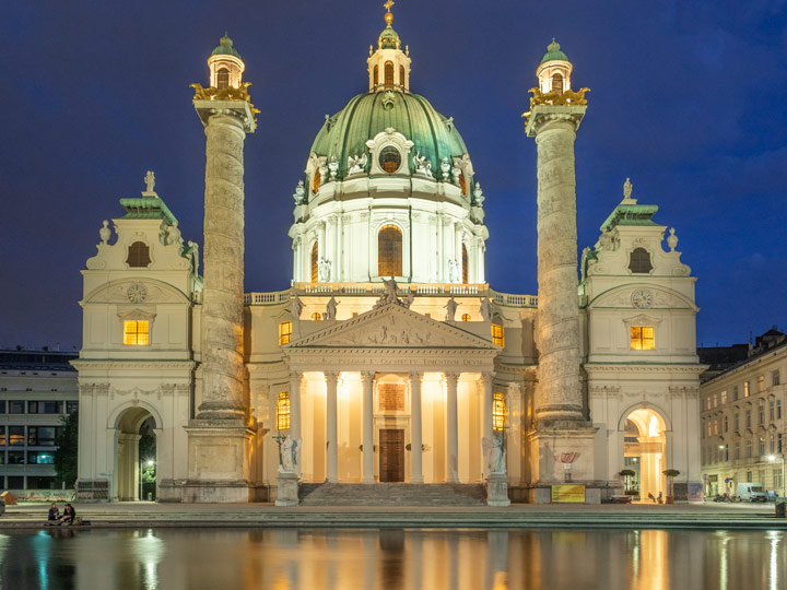 Vienna Karlskirche at night with water reflection.