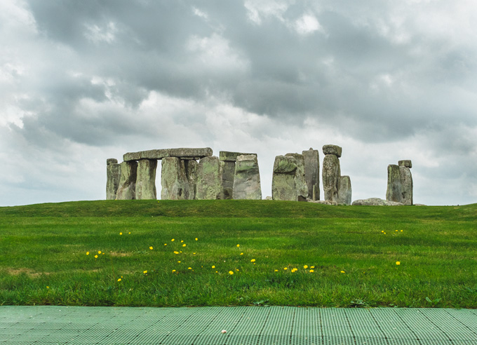 How to visit Stonehenge for free and get this amazing view of the stone circle with grassy hill in foreground.