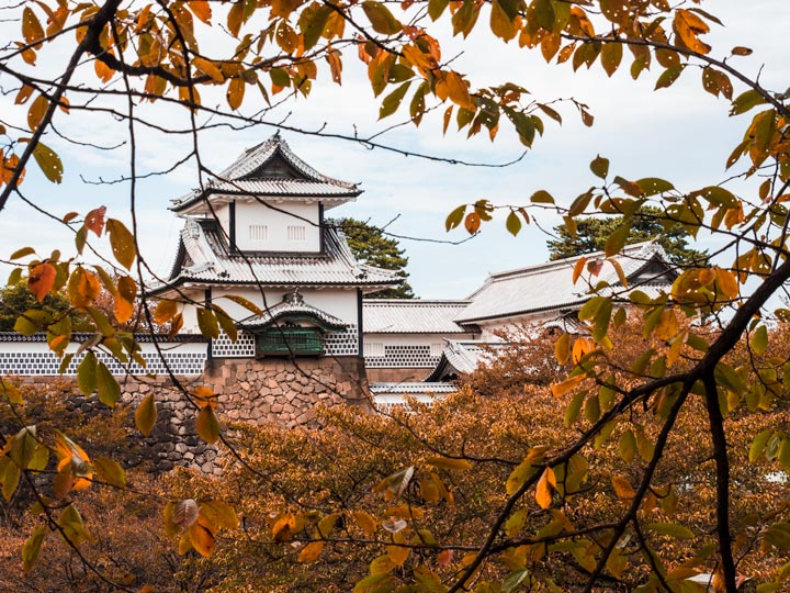 Kanazawa castle viewed through orange autumn leaves.