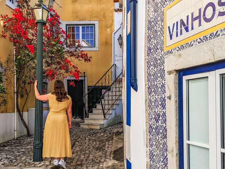 Girl in yellow dress in Cascais alley with flowers.