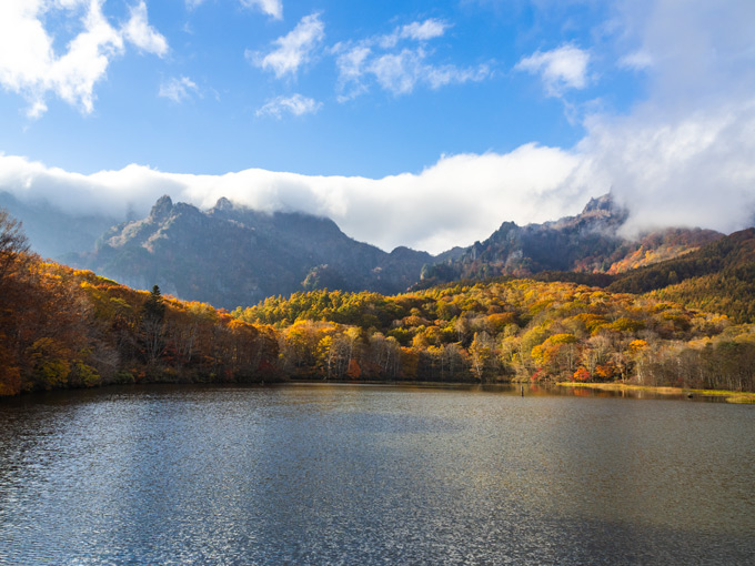 Kagami Lake in Togakushi, Nagano with autumn trees across water.